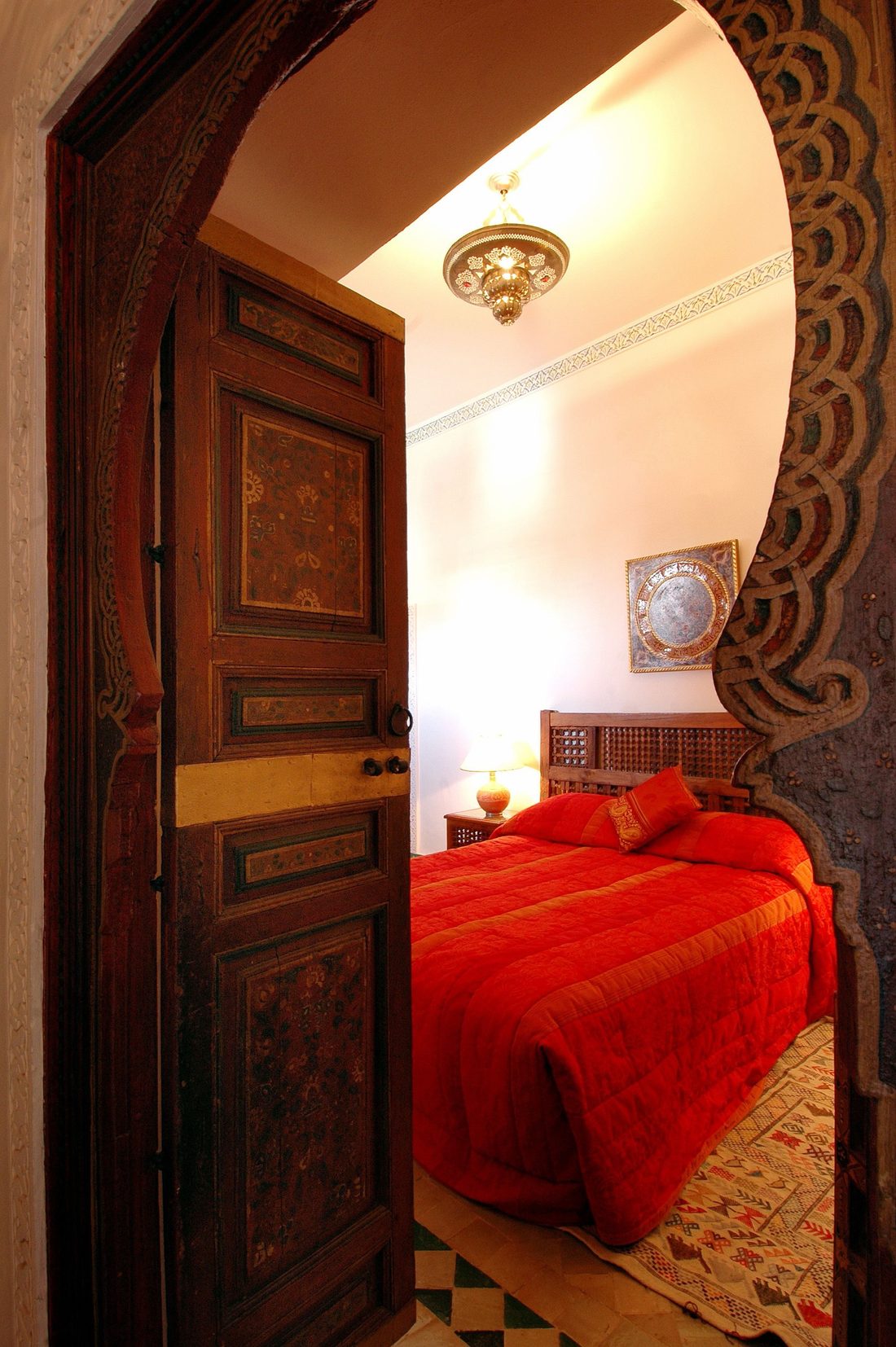 Porte marocaine sculptée ouvrant sur une chambre de riad